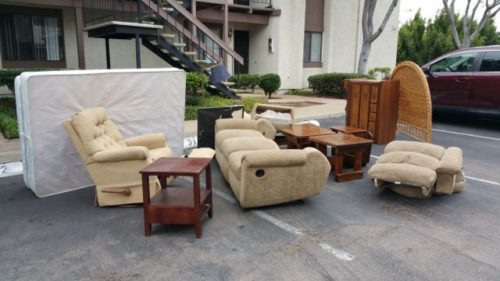 Couch, recliners, and tables staged in an apartment parking lot