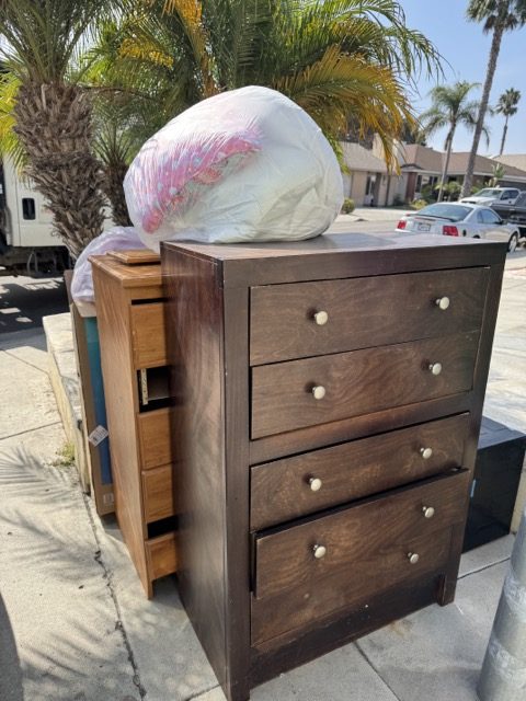 Two dressers and bagged bedding staged on a San Diego sidewalk