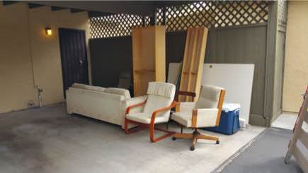 Sofa, chairs, and bookshelves staged under a carport